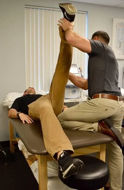 Therapist stretching a patient’s hamstring at Deer Park Physical Therapy
